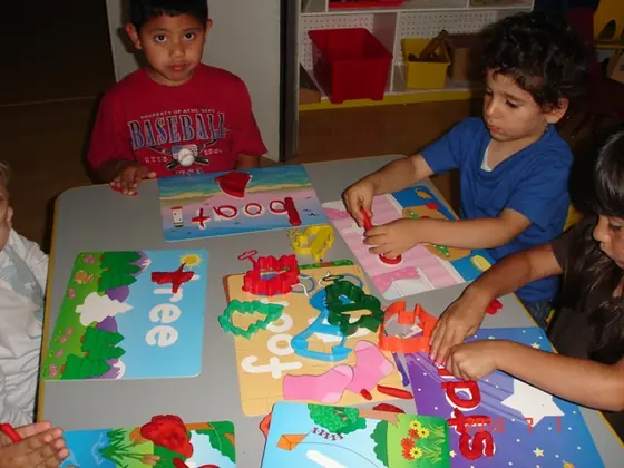 Children shaping play dough letters at a table of word cards