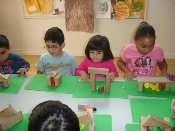 Children building with wooden blocks on green mats