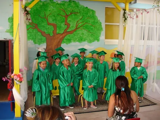 Children in green caps and gowns at a graduation celebration