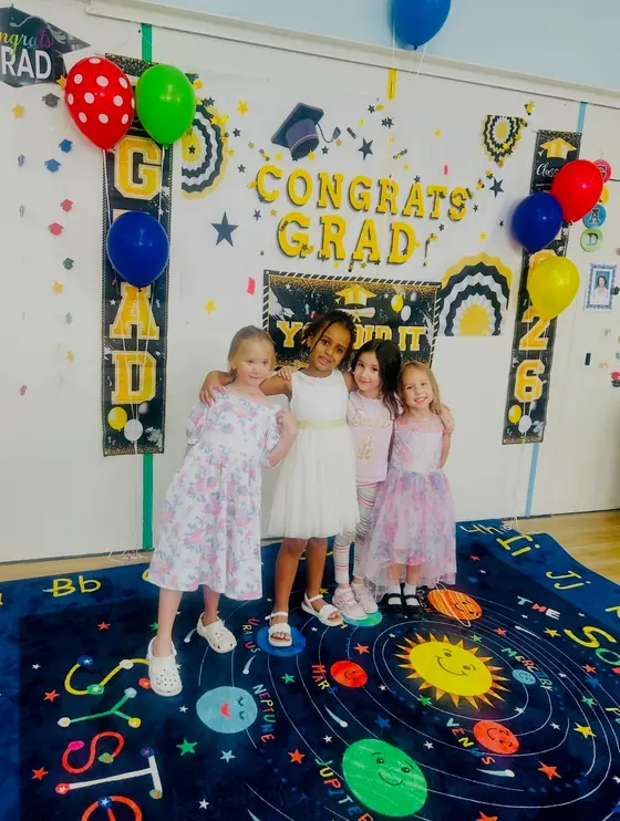 Four children in front of a Congrats Grad banner
